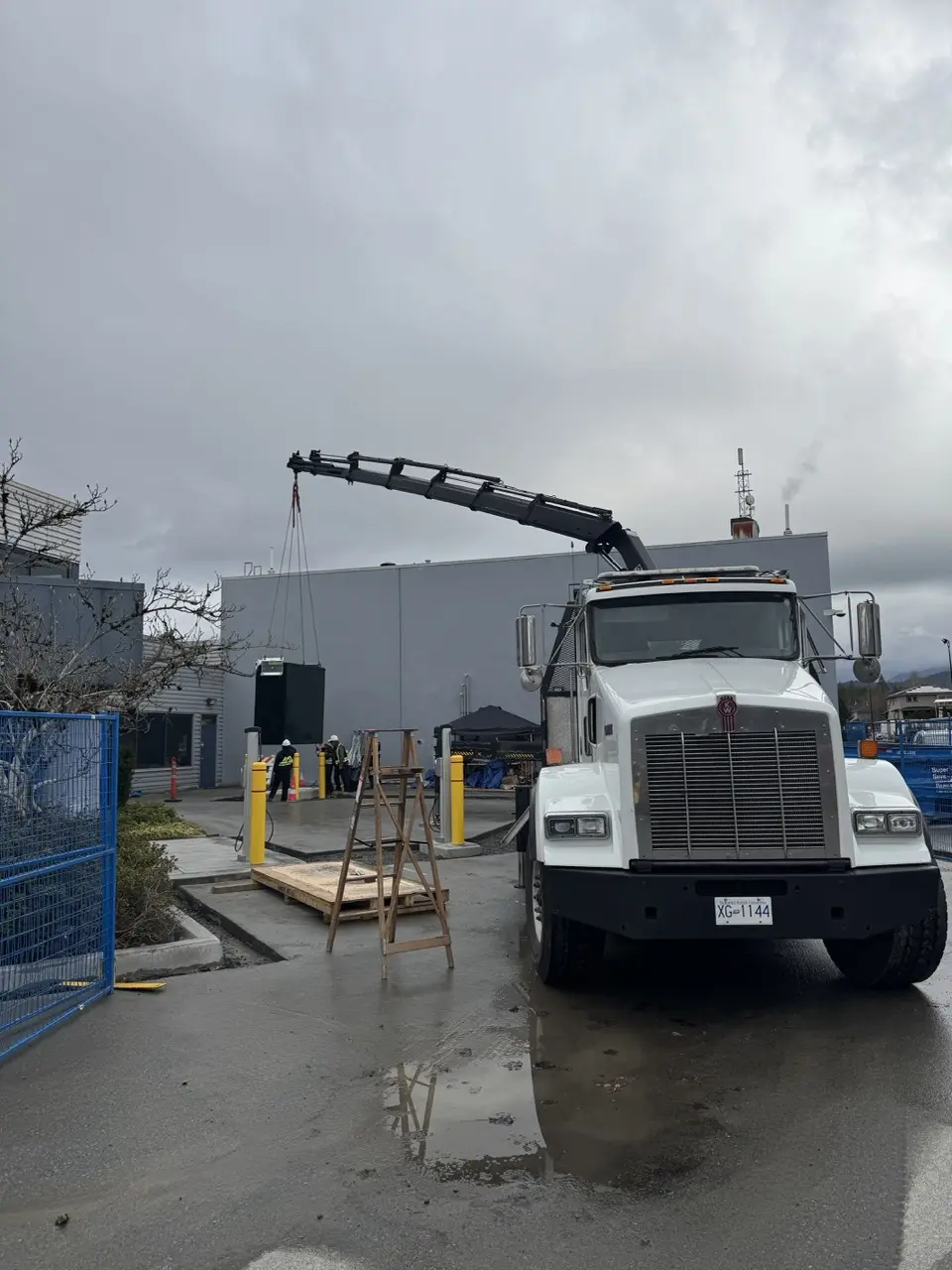 Crane truck positioning an outdoor electrical kiosk at a project site