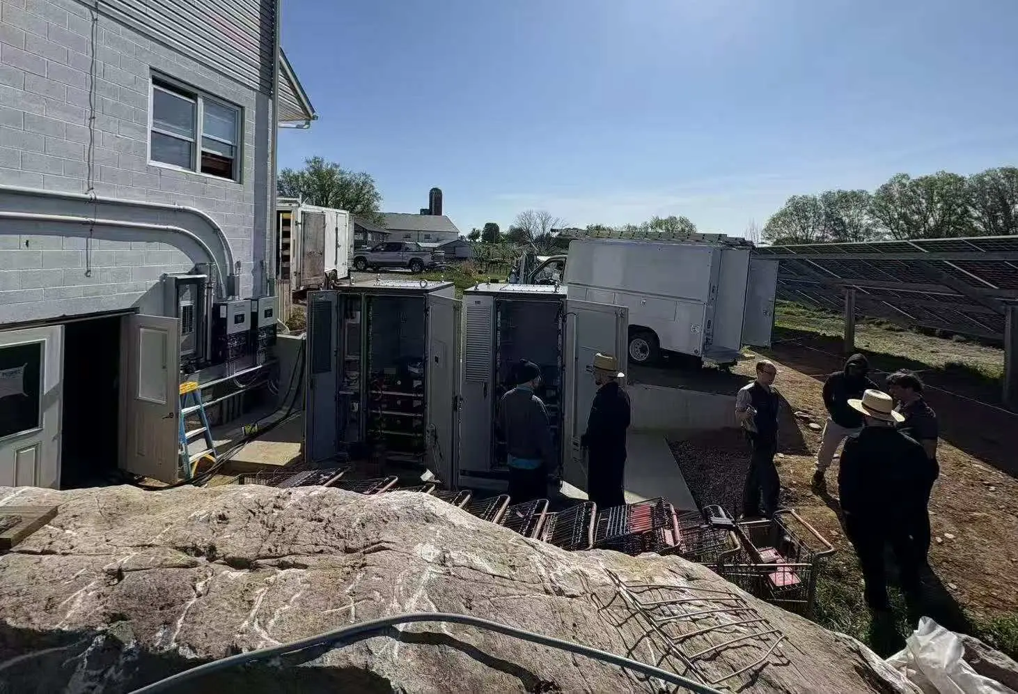 Commercial battery energy storage cabinets during installation beside a solar array